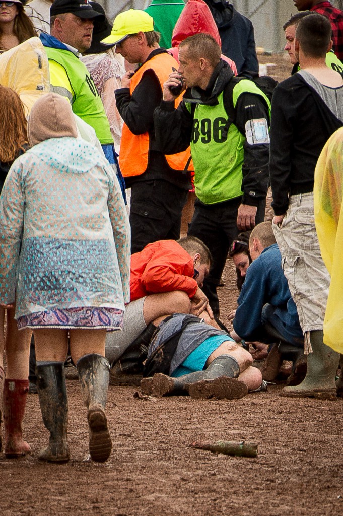 T in The Park, 2015, Day two. T in The Park has it's first day on it's new site at Strathallan Castle. Thousands of festival goers brave the rain to attend the 22nd TiTP. IN PIC................. Security attempt to revive a reveler between the campsites and the arena. (c) Wullie Marr/DEADLINE NEWS For pic details, contact Wullie Marr........... 07989359845