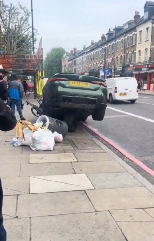 The crash somehow left the BMW balanced in the air on top of one of it's wheels.