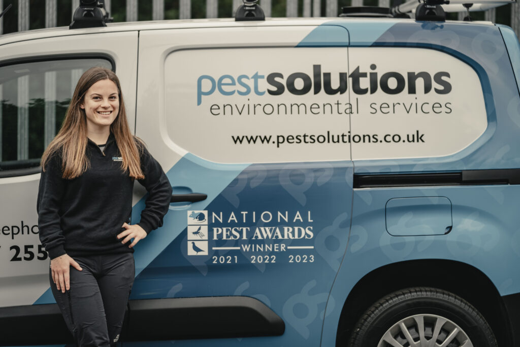 Masie Bullock stands next to a Pest Solutions band. Image supplied with release by Spreng Thomson.