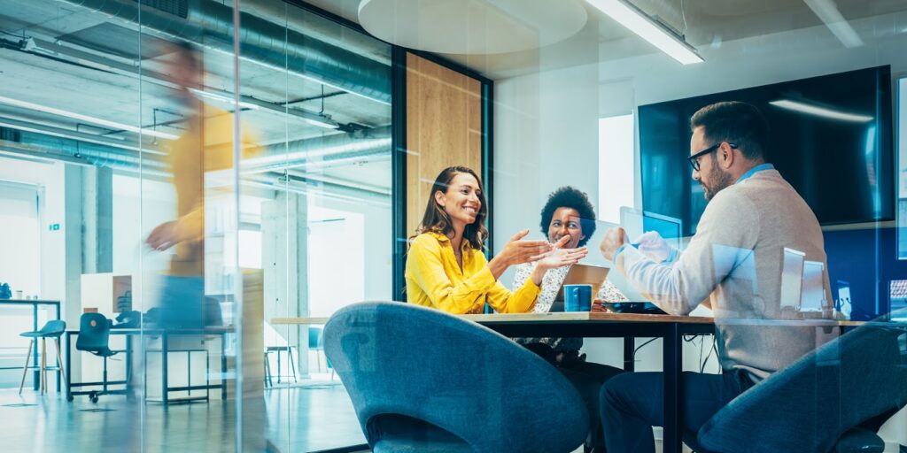 People at a desk having a conversation in an office. Image supplied with release by hot tin roof.