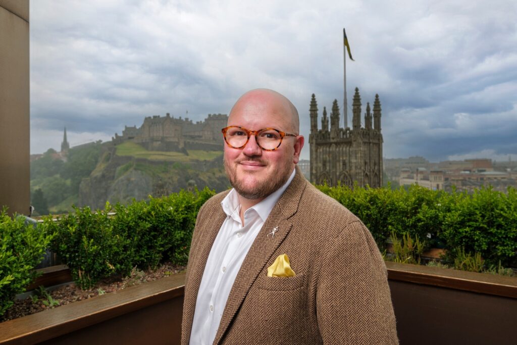 Dafyyd Pugh Williams smiles in his headshot. Image supplied with release by Frame Creates.