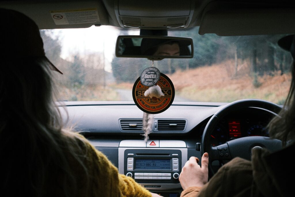 Driver and passenger behind wheel of a car. Photo by Jaz Blakeston-Petch on Unsplash  