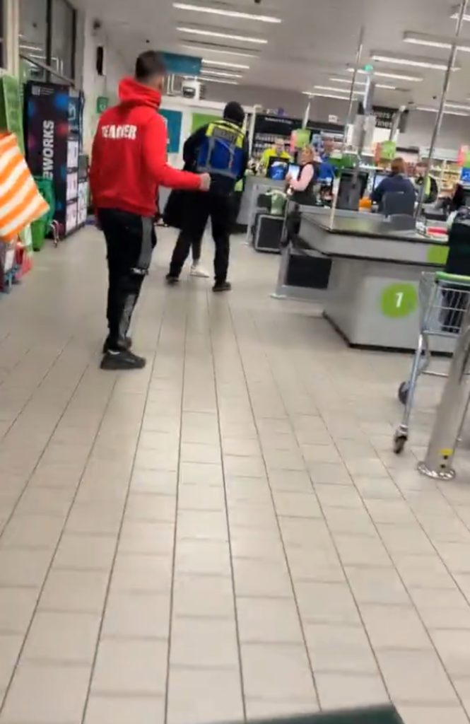 WATCH the shocking moment an Asda security guard lets out all of his anger on an apparent shoplifter, forcing her to remove her jacket to reveal hoards of stolen coffee.