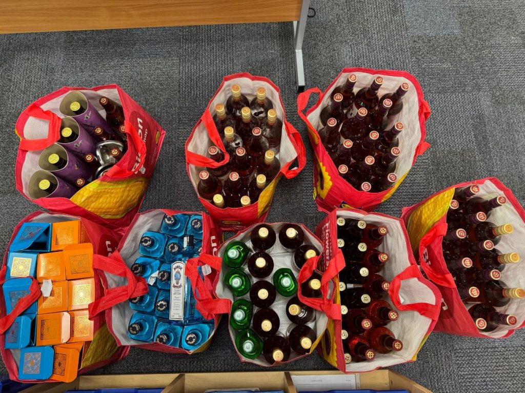 An image of eight heavy-duty shopping bags full of bottles of alcohol.