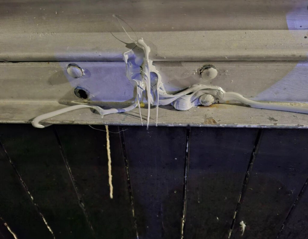 An image of a metal shutter, its lock covered in white filler.