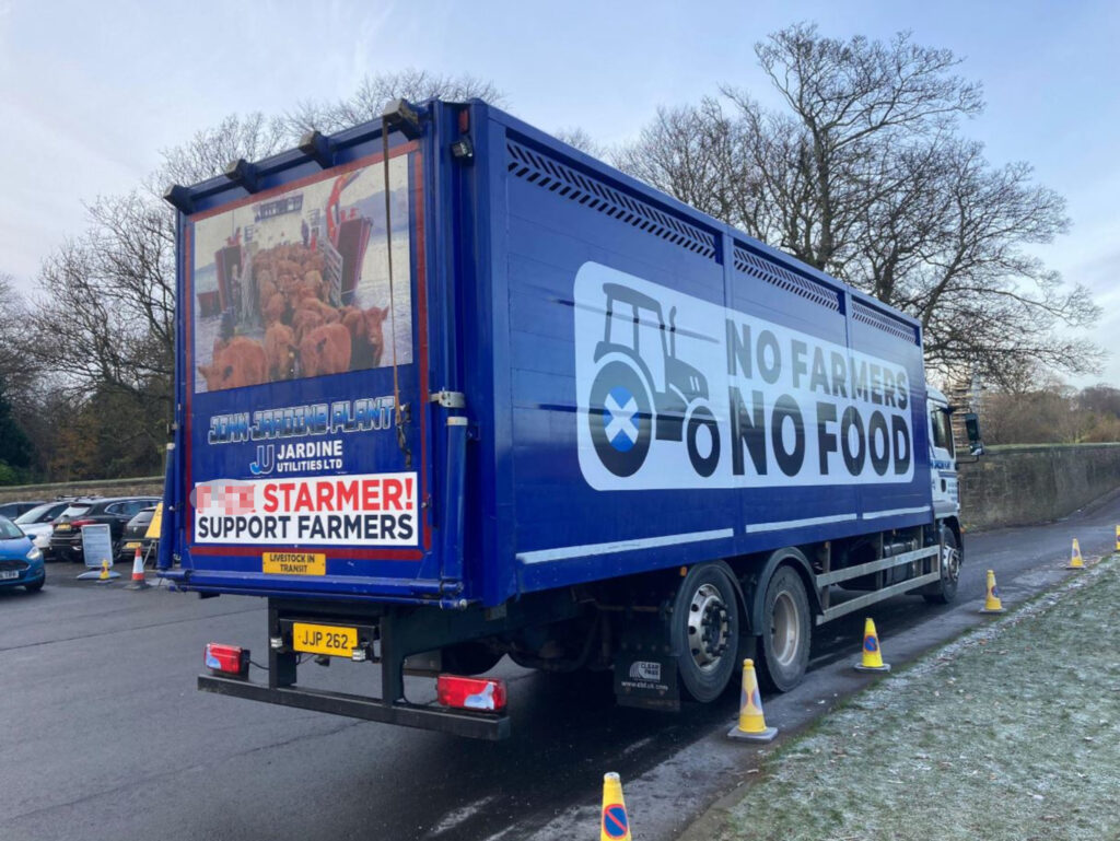 An image of a blue lorry parked at the side of a road, printed with slogans.