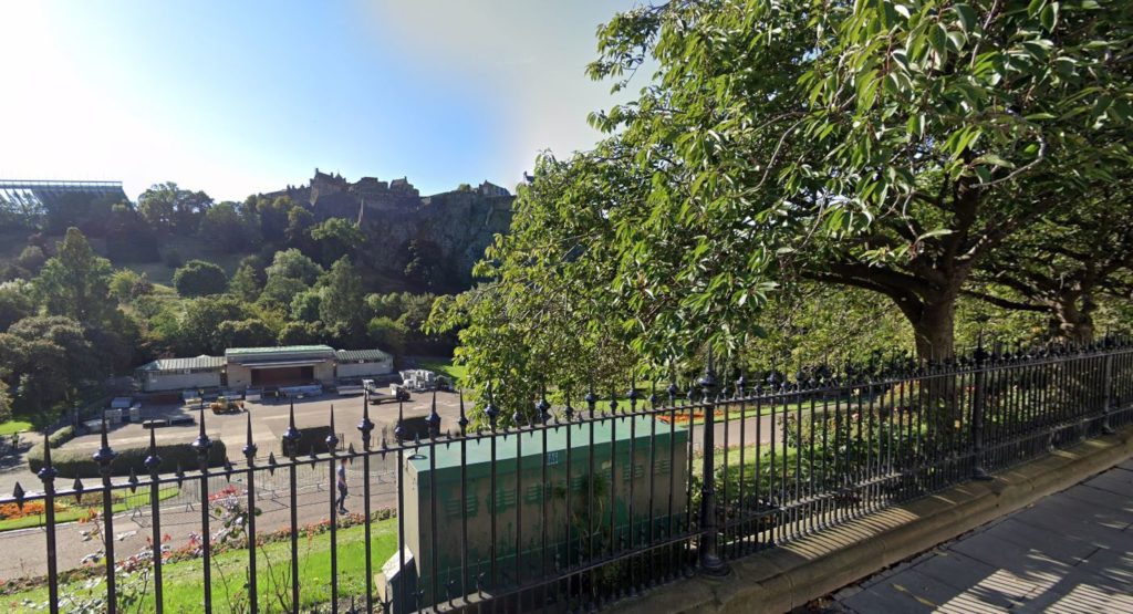 An image of a park space visible at a distance from behind black railings.