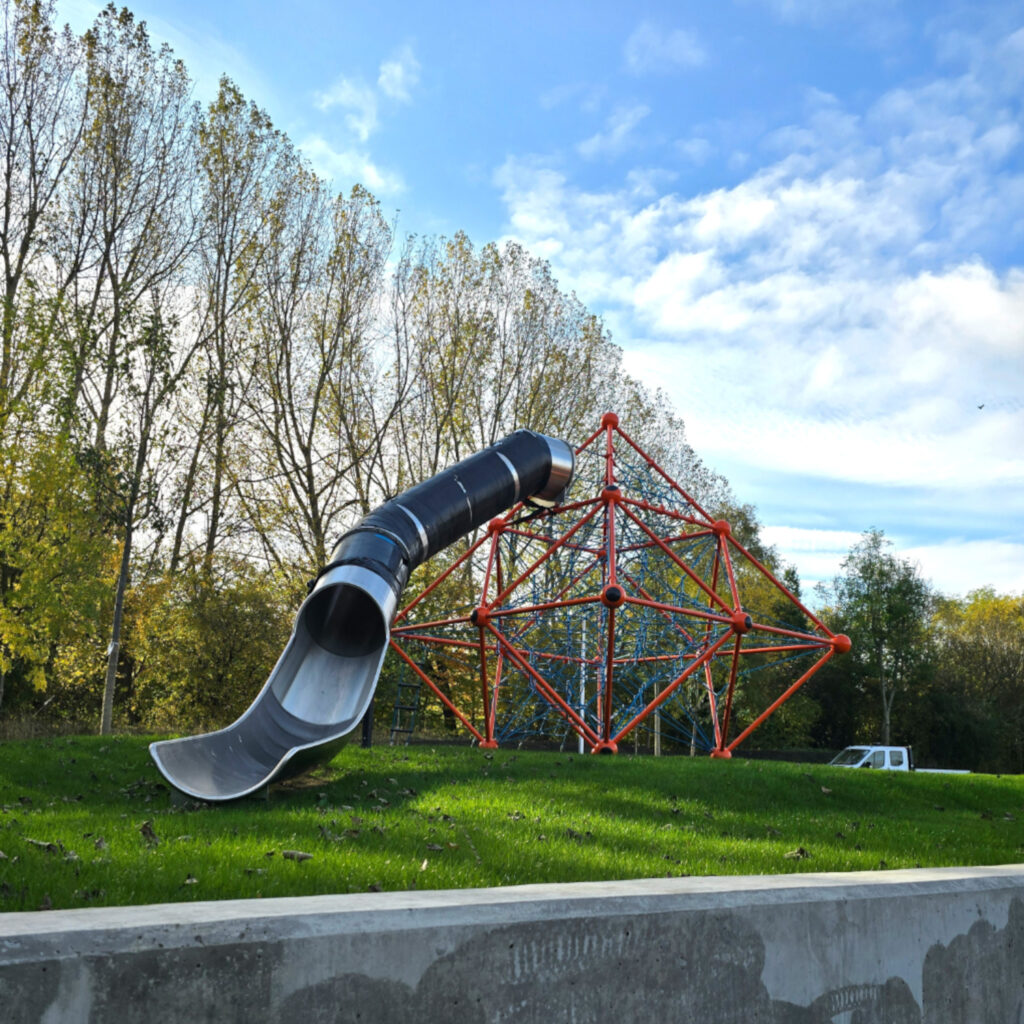 An image of a red metal playground climbing frame with a silver slide.