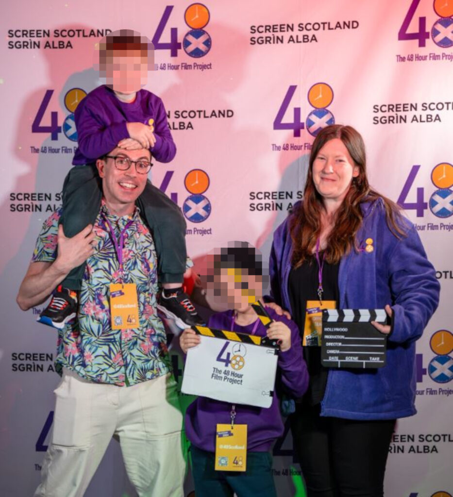 An image of a man, woman and two children. One of the children sits on the man's shoulders.