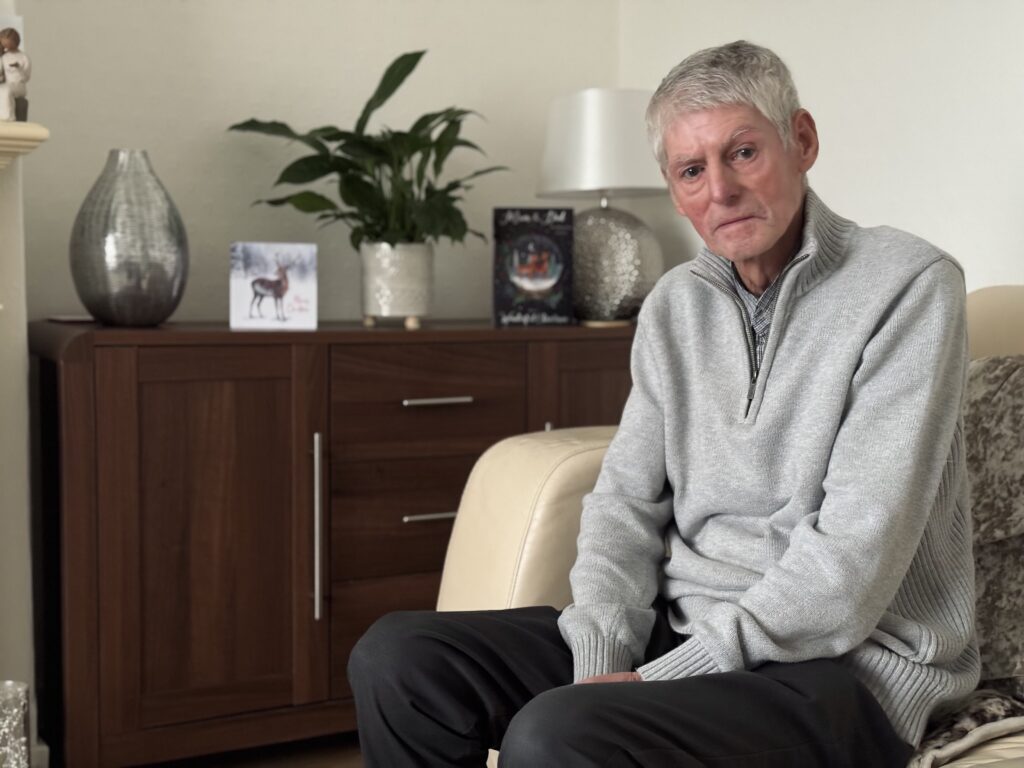 An image of John McCrae, who developed silicosis, sitting on the couch.