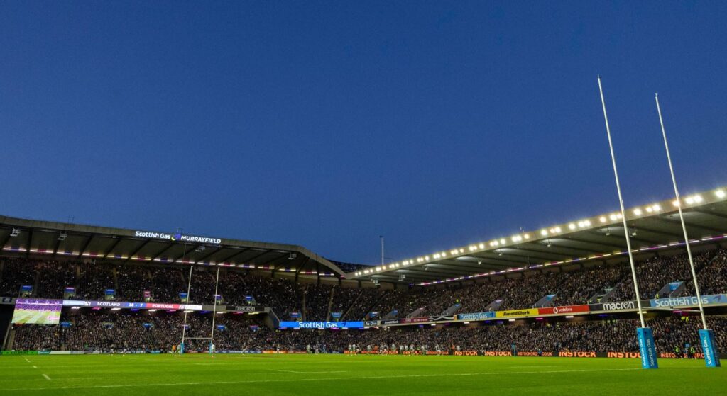 An image of a full rugby stadium under a darkening sky.