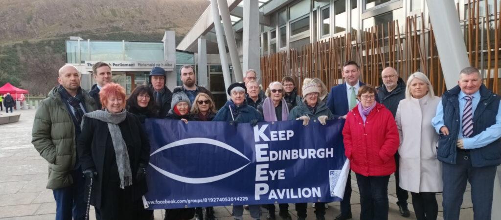 An image of a group of people holding a purple banner reading: "Keep Edinburgh Eye Pavilion"