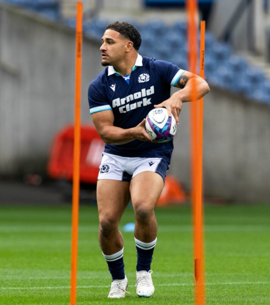 An image of a man in a blue and white rugby strip, holding a rugby ball.