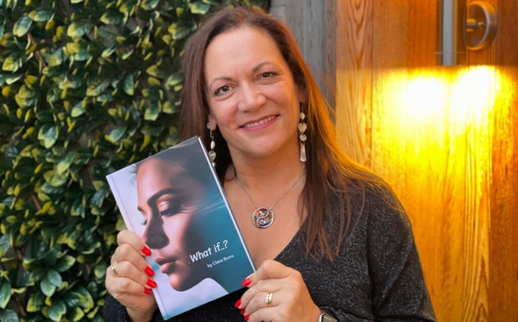 Author Claire Burns posing with her debut novel What If..?