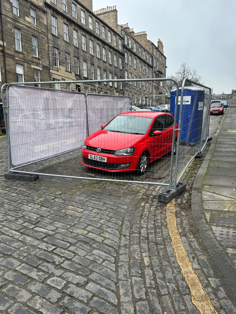 The fences appear to have been set up to create a private parking space. (C) Bluesky.