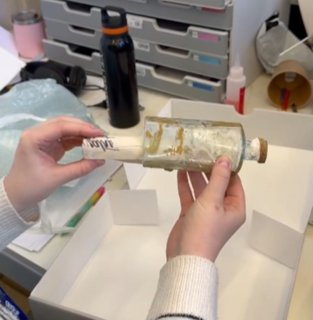 The team carefully extracted the note after the bottom of the bottle had been removed. (C) @Captheatres/Instagram