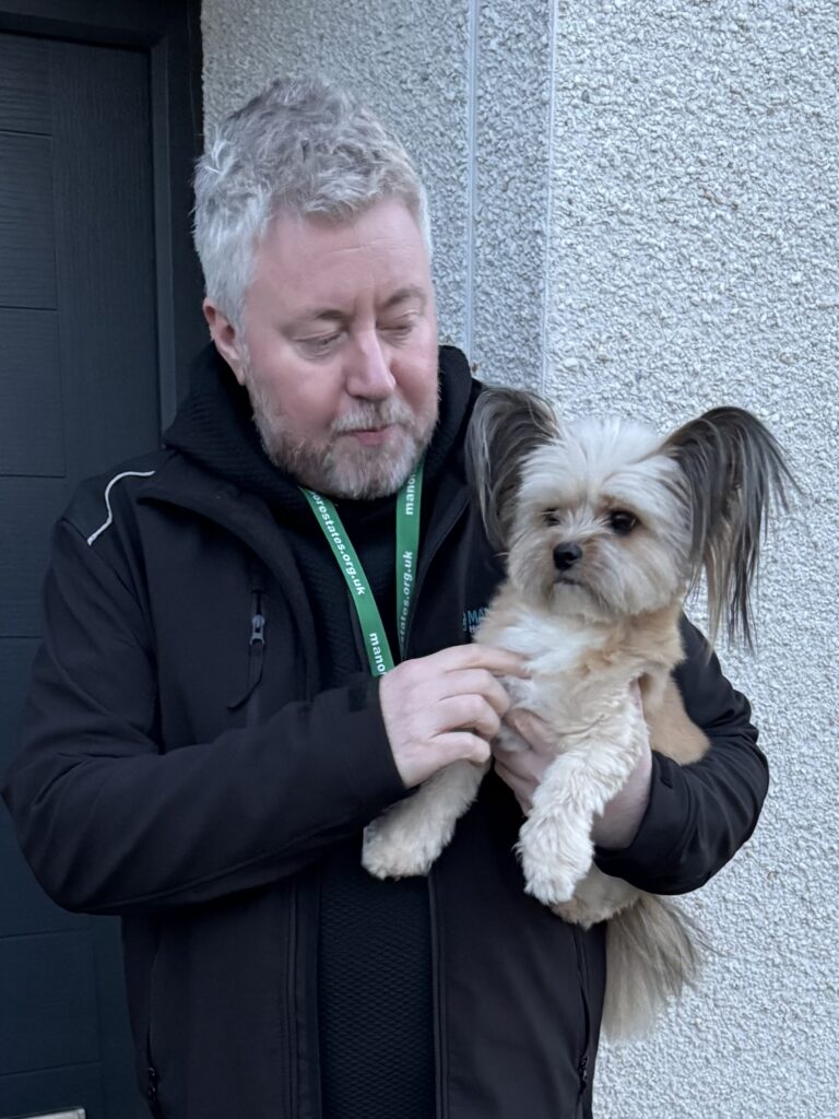 An image of Alasdair Fraser, the housing manager of Manor Estates Housing Association, holding a dog.